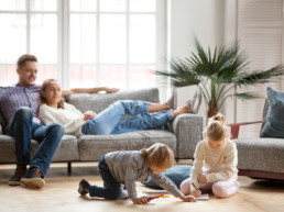 Young parents watch children play with markers in living room. Modern home with contemporary finishes, this family lives in a duplex in Edmonton.